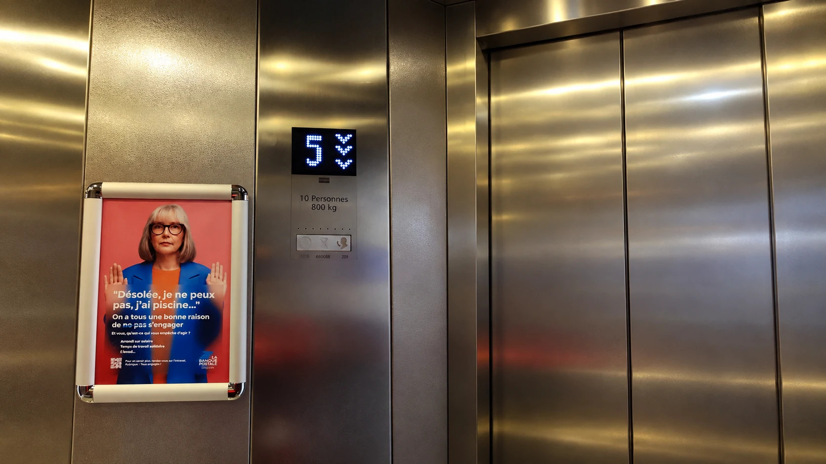 La Banque Postale : affiche Tous engagés à côté des portes d’un ascenseur